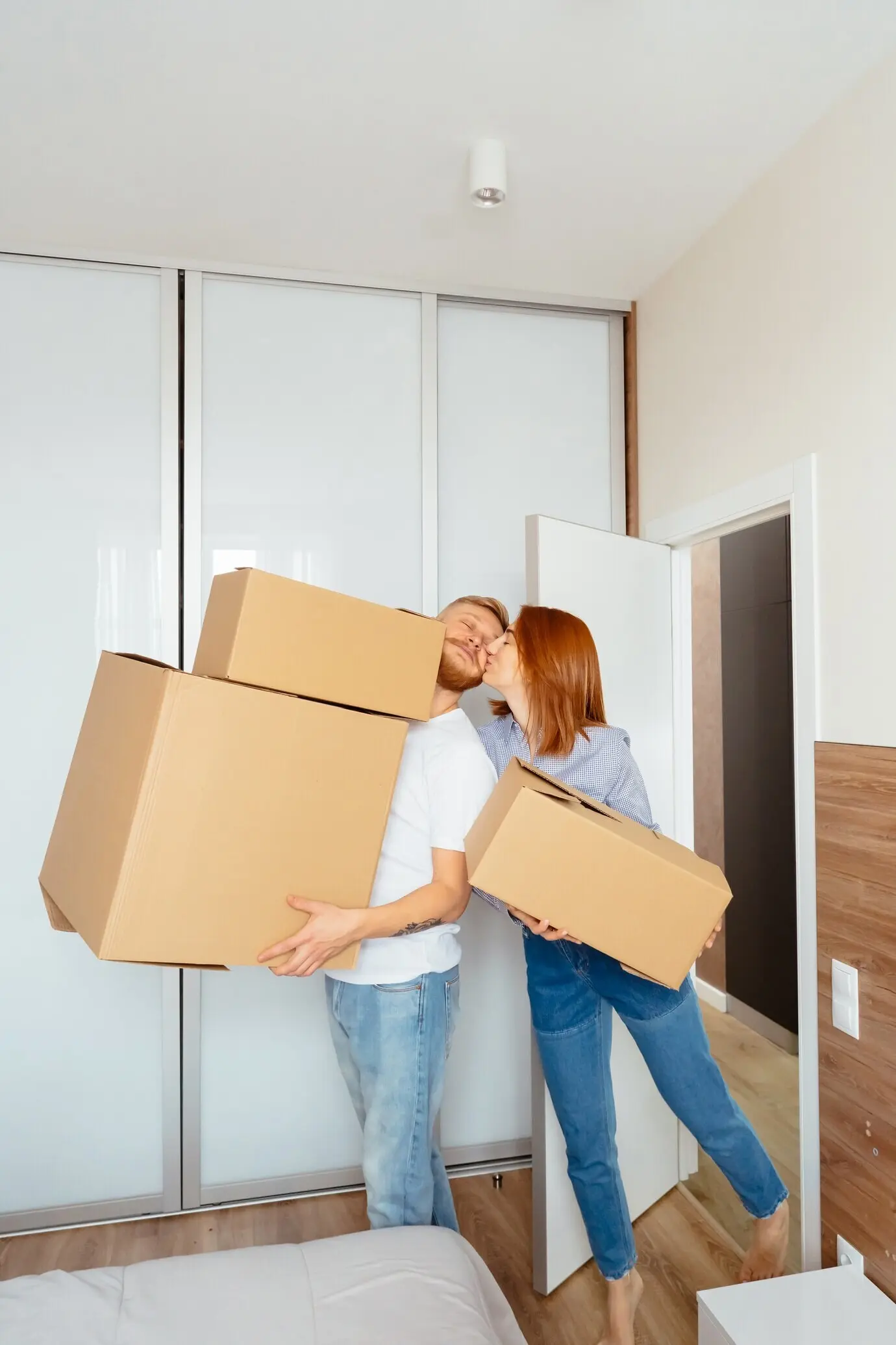 Joyful couple holding cardboard boxes as they move to a new place.